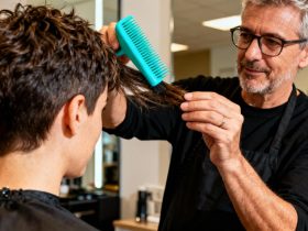 Coiffeur européen de 45 ans réalisant une coupe pixie courte et texturée sur une cliente, avec brosse turquoise